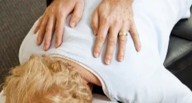 Chiropractor's hands on a patient's upper back